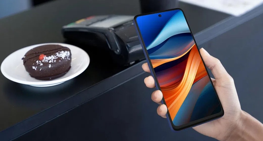 Mobilní telefon TCL 50SE / 128 GB šedý Mobilní telefon TCL 50SE 128GB Space Grey je zachycen v kavárně při platbě prostřednictvím bezkontaktního placení mobilním telefonem.