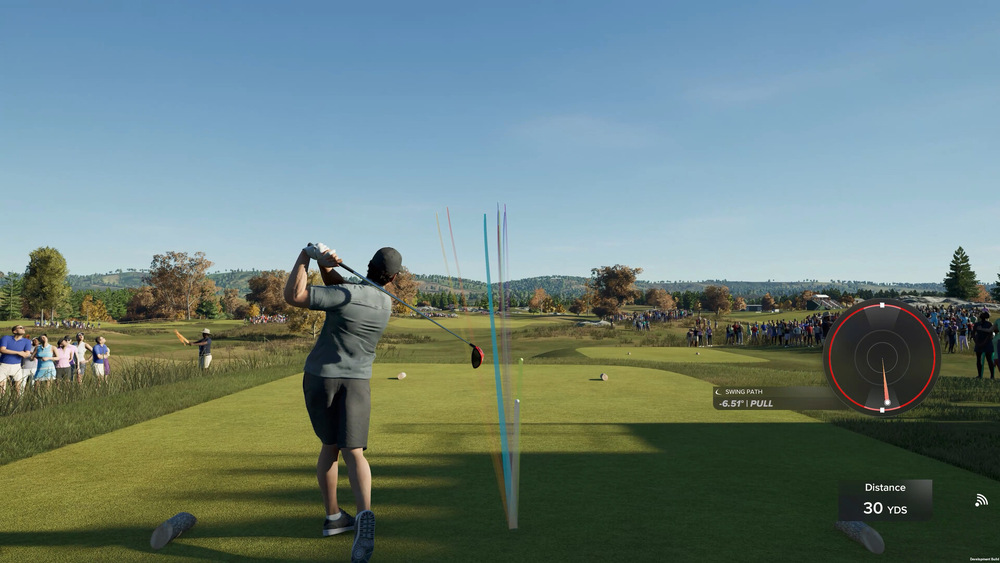 Golfista odpaluje na svěžím, sluncem zalitém hřišti, diváci v jeho blízkosti. Grafy a měřič vzdálenosti překrývají obraz, což naznačuje, že se jedná o videohru.