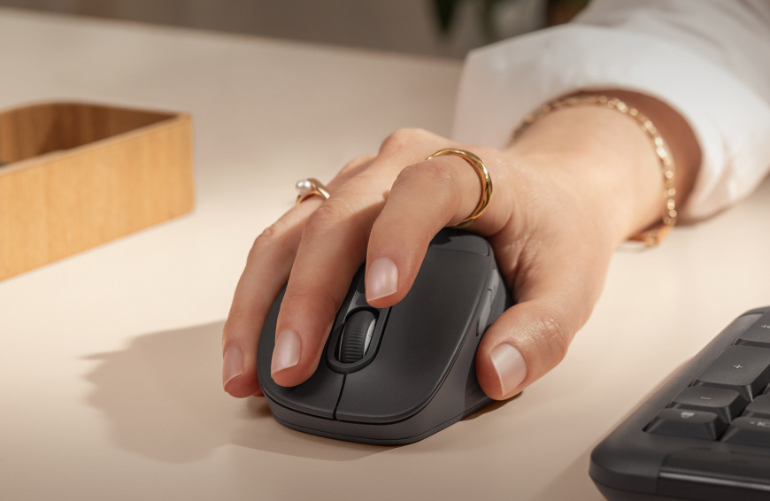 Ruka položená na myši Logitech Signature M850 L Wireless při práci u stolu