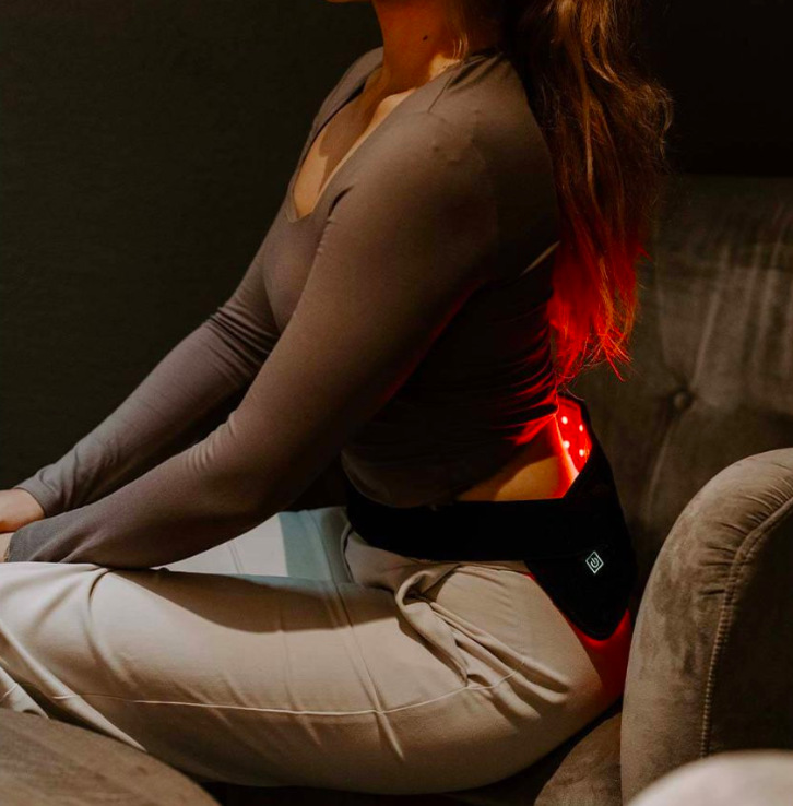Žena používá nastavitelný návlek pro LED terapii upevněný kolem bederní oblasti zad