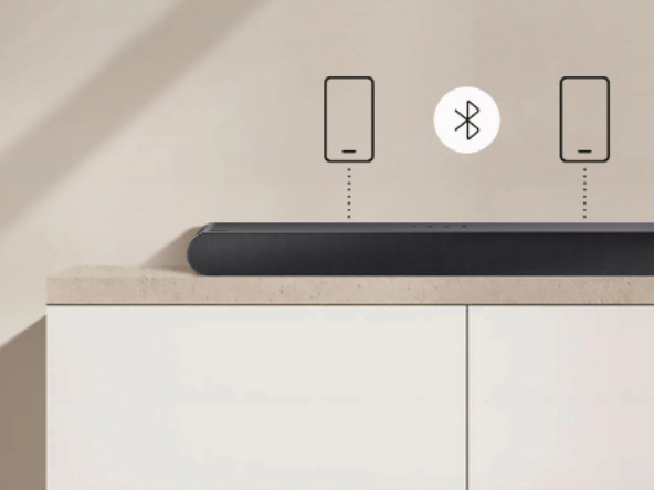 Soundbar Samsung HW-S50B černý Soundbar Samsung leží na skříňce, nad ním jsou dvě ikonky mobilního telefonu spojené se soundbarem tečkovanou linkou, mezi telefony je logo Bluetooth