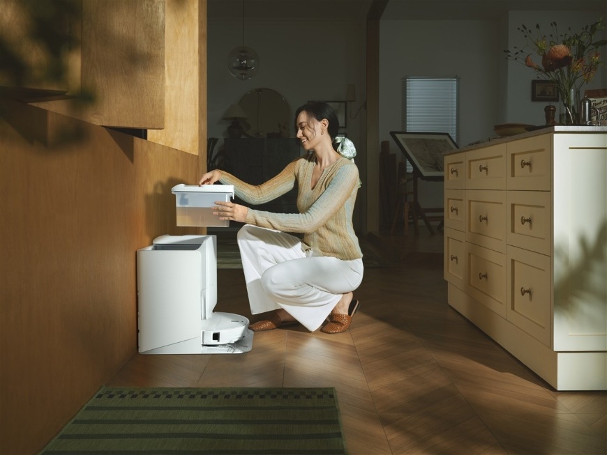 Usmívající se žena drží zásobník s čistou vodou do dokovací stanice pro robota Qrevo Edge 2 Pro