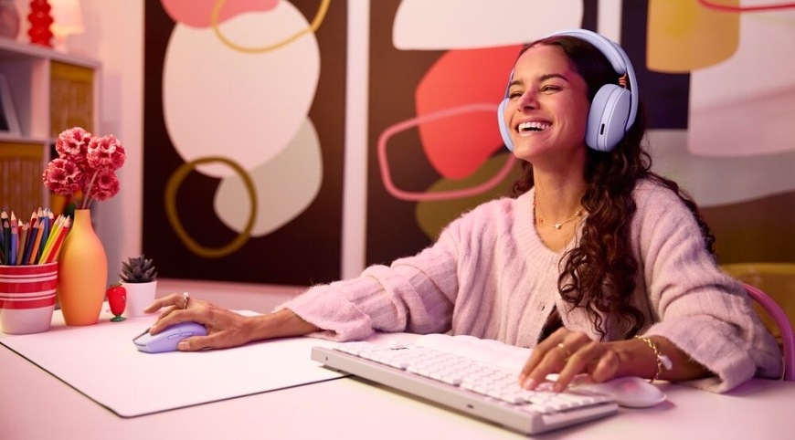Hráčka u počítače hraje hru se světlým herním headsetem Logitech G325 LIGHTSPEED Wireless na hlavě