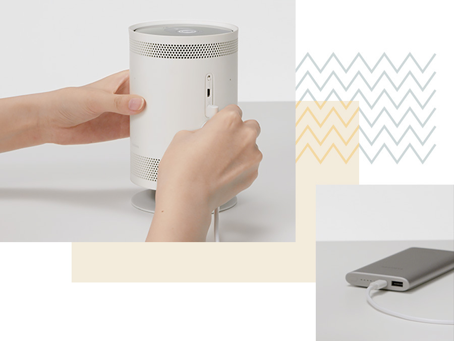 Projektor Samsung The Freestyle SP-LFF3CLA 2.gen. bílý Koláž dvou obrázků, vlevo nahoře na větším obrázku ruce zapojují nabíjecí kabel do projekoru Samsung The Freestyle Sp-LFF3CLA 2. gen., vpravo dole na menším obrázku je nabíjecí kabel zapojen do powerbanky