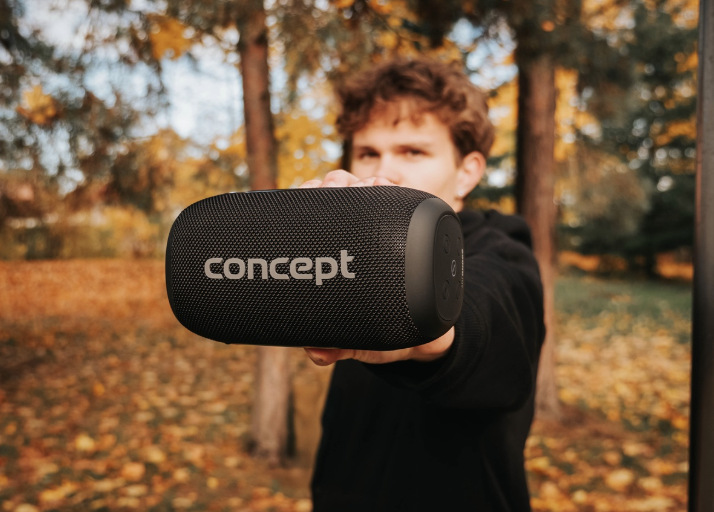 Mladý muž drží přenosný reproduktor Concept SoundJoy BR5020 v podzimním parku