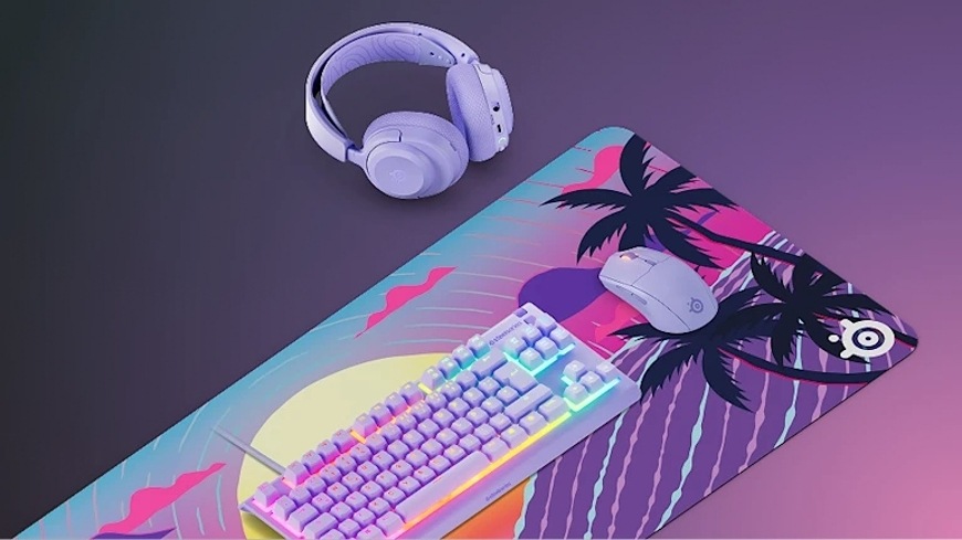 Podložka pod klávesnici a myš SteelSeries QcK XXL Neon Sunset fialová Podložka QcK XXL Neon Sunset pod klávesnicí a myší, vedle ní headset na stole