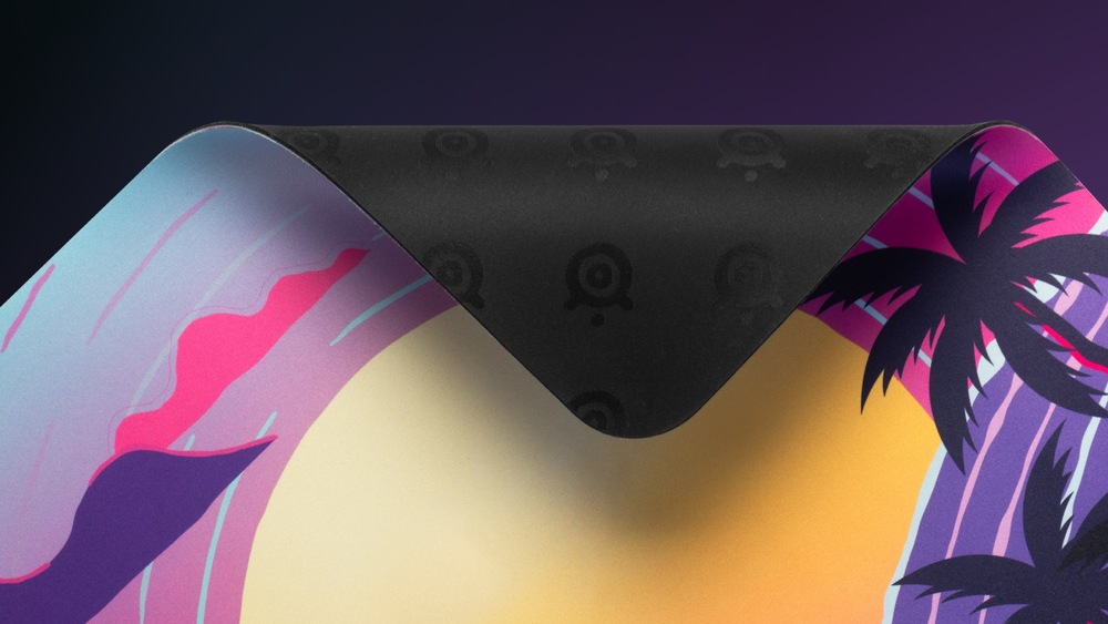 Podložka pod myš SteelSeries QcK Large, Neon Sunset fialová Odklopený roh podložky QcK Neon Sunset odhalující gumovou spodní stranu