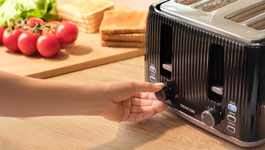 Topinkovač Sencor STS 7541BK černý Žena otáčí ovládací kolečko topinkovače Sencor vedle připravených toastů a rajčat.