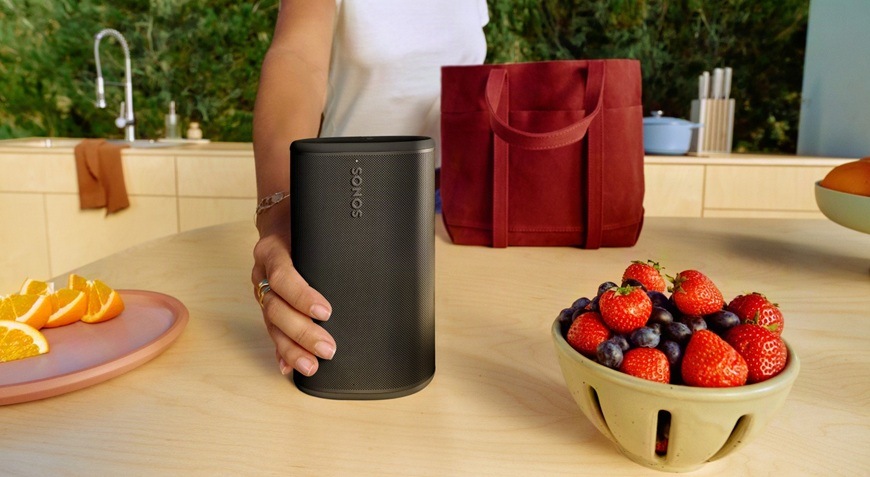 Přenosný reproduktor SONOS Play bílý Žena pokládá reproduktor na kuchyňskou linku.