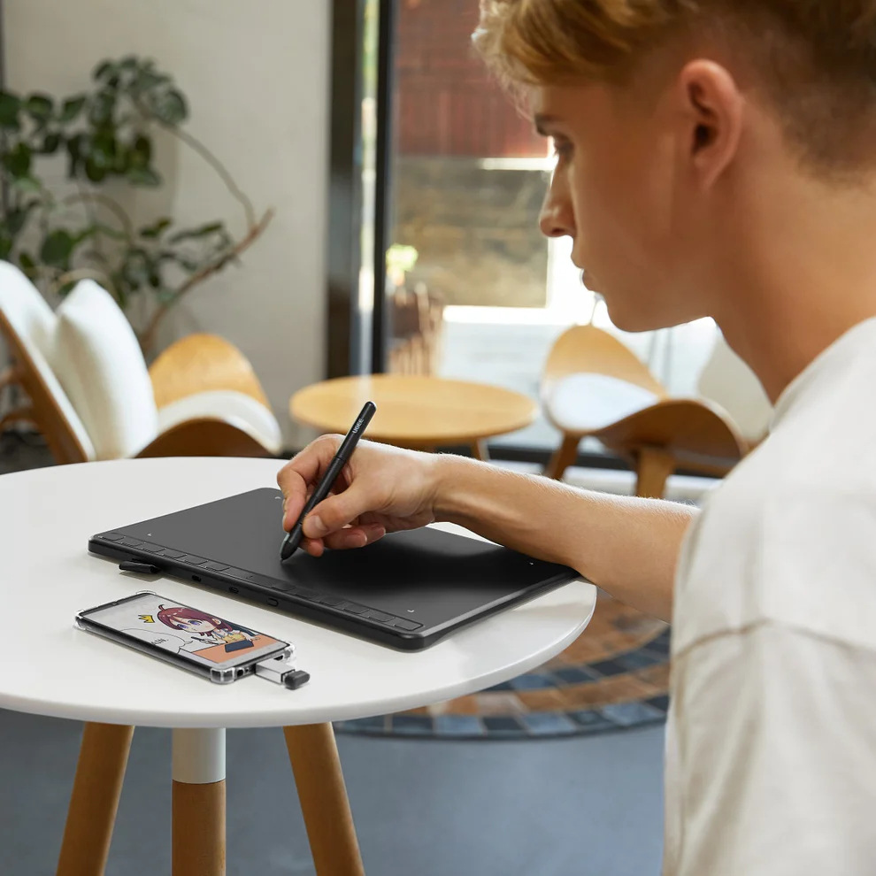 Muž kreslí pomocí stylusu na tabletu UGEE S640, obrázek se promítá na displeji smartphonu