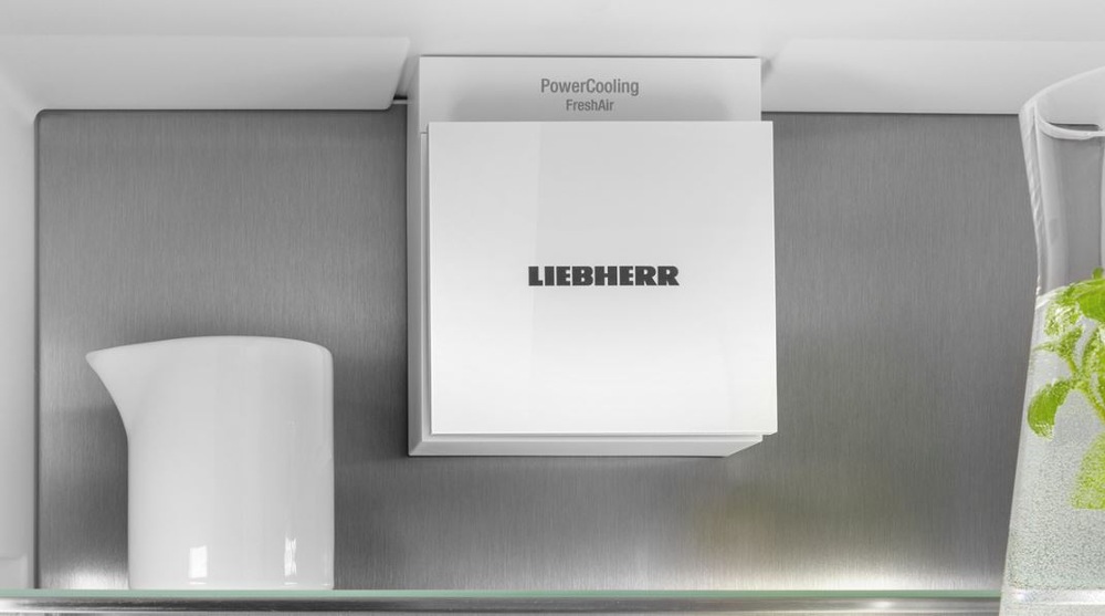 detail na ventilátor powercooling v lednici liebherr se s nerezovou zadní stěnou. Vedle je karafa na vodu s mátou