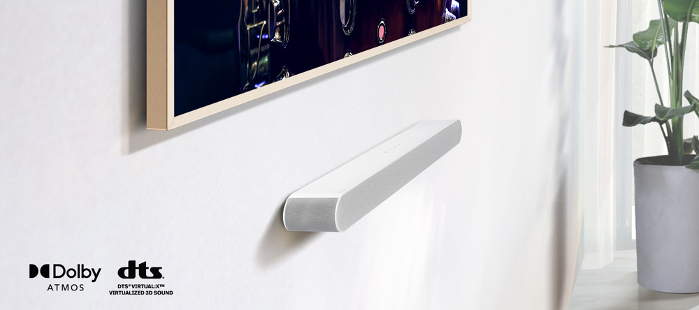 Soundbar Samsung HW-S61D bílý Soundbar Samsung HW-S61D je připevněný na zdi pod televizí, v levém dolním rohu jsou loga DOlby ATMOS a DTS