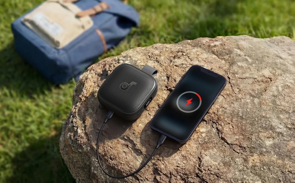 Přenosný reproduktor Anker Soundcore Boom Go 3i černý Anker Soundcore Boom Go 3i při nabíjení smartphonu v přírodě
