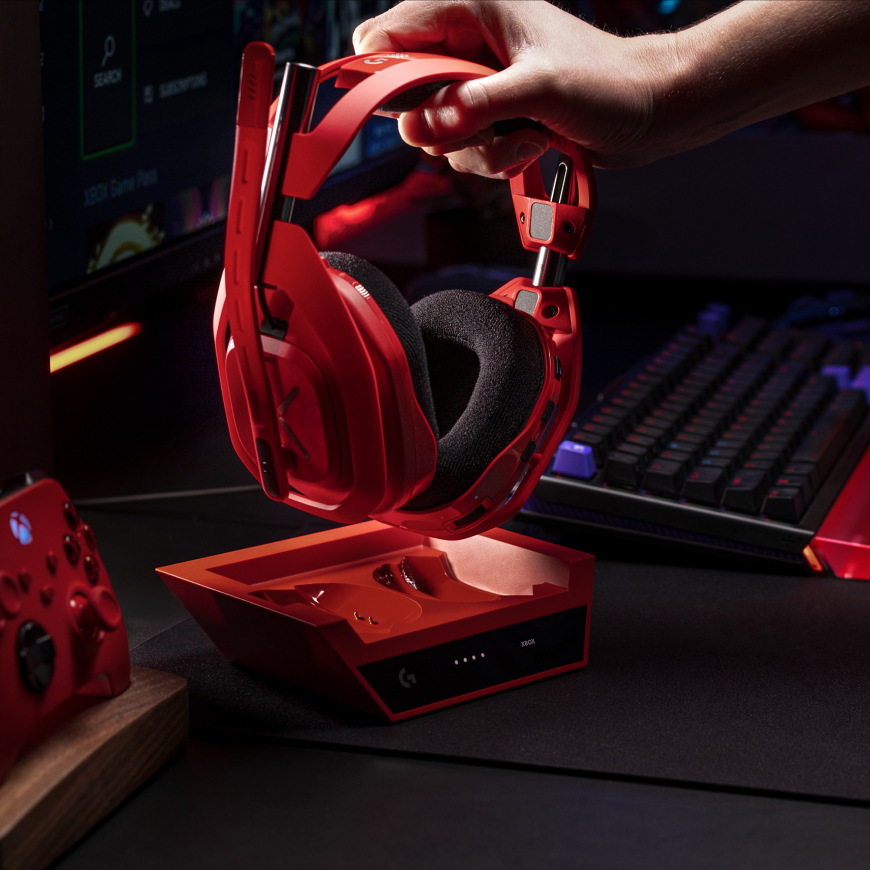 Headset Logitech G Astro A50 X Lightspeed Wireless + Base Station červený Ruka zvedající headset Logitech G A50 X LIGHTSPEED z nabíjecí základny na herním stole