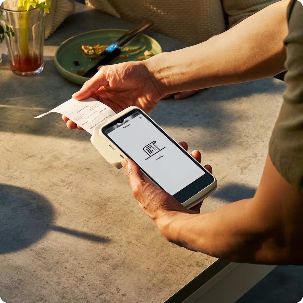 Obsluha tiskne účtenku na SumUp Smart Terminal s tiskárnou na stole restaurace.