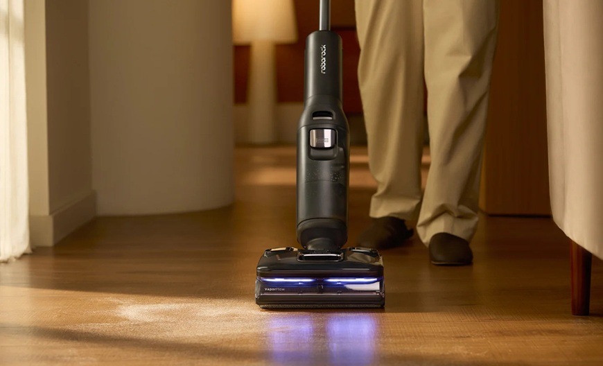 Muž vysává s vysavačem Roborock F25 Ultra v obývacím pokoji. Vysavač je opatřen modrým světlem.
