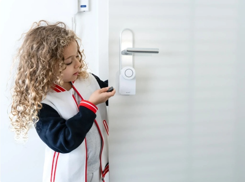 Dítě otvírající dveře s Nuki Smart Lock pomocí dálkového ovladače Nuki Fob.