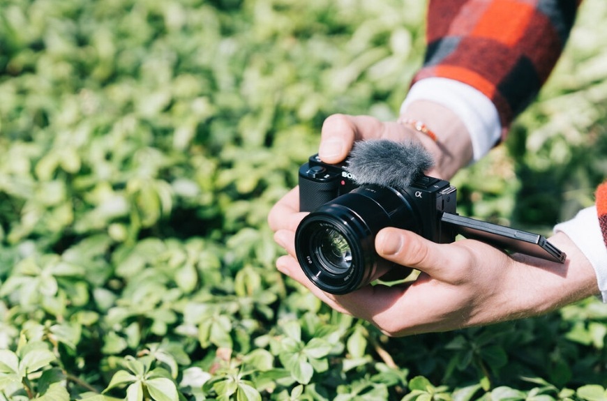 Fotoaparát Sony ZV-E10 v dlaních fotografa při snímání zeleně