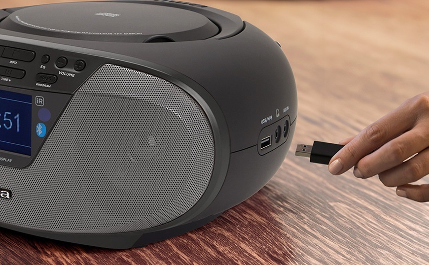 Radiomagnetofon s DAB+/CD AIWA BBTU-500DAB černý Detailní záběr na bok radiopřijímače DAB+/CD Aiwa BBTU-500DAB v černém provedení, kde žena zapojuje USB flashdisk.