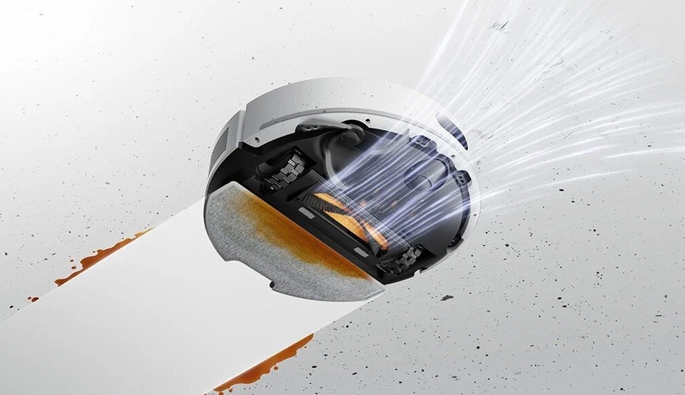 Robotický vysavač Dreame F20 bílý Pohled zespodu na robotický vysavač Dreame F20, který nasává nečistoty a zároveň za sebou nechává čistou vytřenou podlahu.