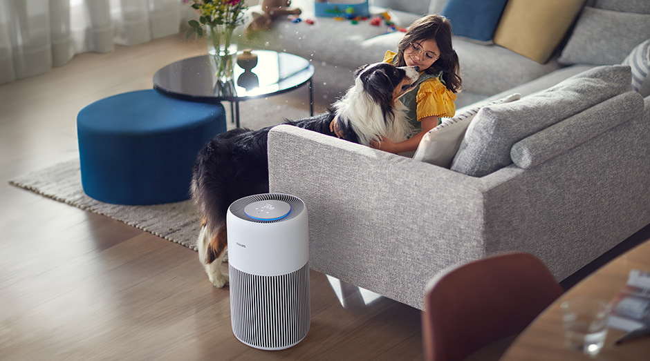 Čistička vzduchu Philips AC2220/10 2000 Series vedle pohovky, na které sedí dívka hladící si psa