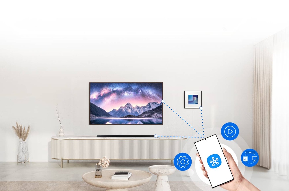Reproduktory Samsung HW-LS60D, Music Frame (2 ks) černé Samsung HW-LS60D, Music Frame visí na zdi obývacího pokoje vedle televizi Samsung, pod níž na televizním stolku leží soundbar Samsung, v popředí ruka drží mobilní telefon, na jehož displeji je logo aplikace SmartThings, tečkované čáry spojují mobil s TV, reproduktorem a soundbarem