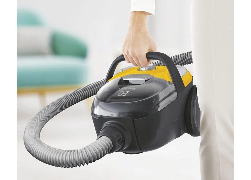 Podlahový vysavač Electrolux CompactGo Cyclonic ECGC21-2Y žlutý Žena drží v ruce vysavač Electrolux ECGC21-2Y CompactGo Cyclonic.