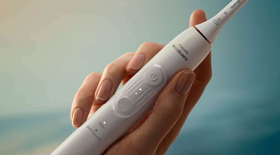 Zubní kartáček Sonicare drží žena v ruce a jdou vidět tlačítka na kartáčku