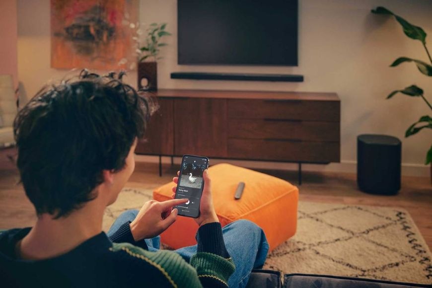 Soundbar JBL BAR 1000 MK2 černý Muž streamuje hudbu do soundbaru JBL BAR 1000 MK2 pomocí telefonu