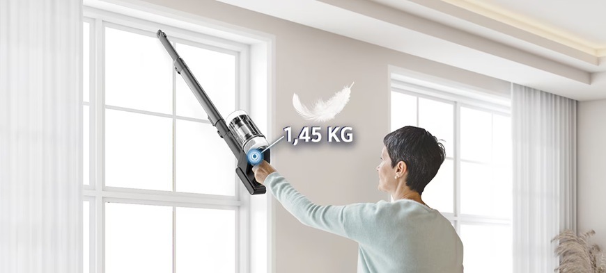 Žena vysává okna tyčovým vysavačem Samsung Bespoke AI Jet VS80F25DES/GE, nad vysavačem je pírko a nápis 1,45 kg