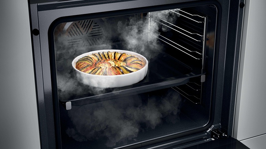obsah otevřené trouby Haier H6 ID2P3B4VYTB, uvnitř se vyskytuje pára a na pekáčku je ratatouille