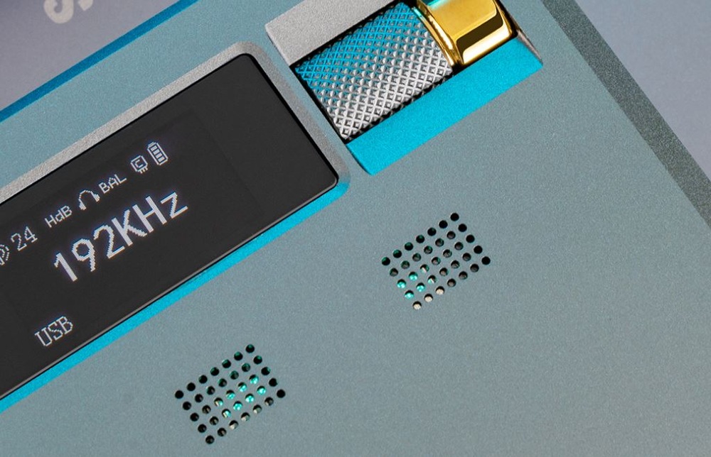 Detail na displej zesilovač zobrazující údaj 192 kHz s USB vstupem. Modrý kovový povrch má větrací otvory a texturovaný knoflík se zlatým akcentem.
