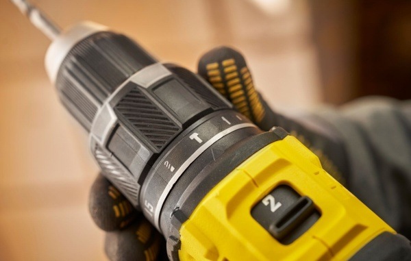 Detail přepínače rychlostí aku vrtačky Stanley FatMax v rukavicí chráněné ruce.