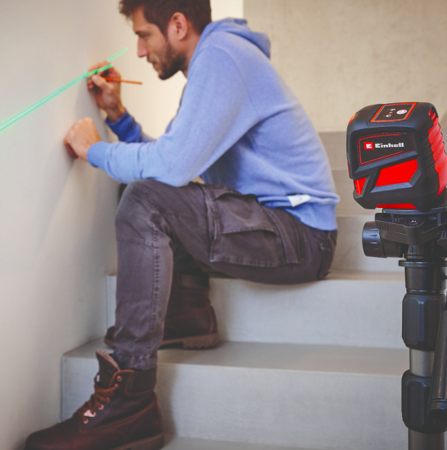 Řemeslník označuje linku na zdi pomocí zelené projekce křížového laseru Einhell TCLL2G