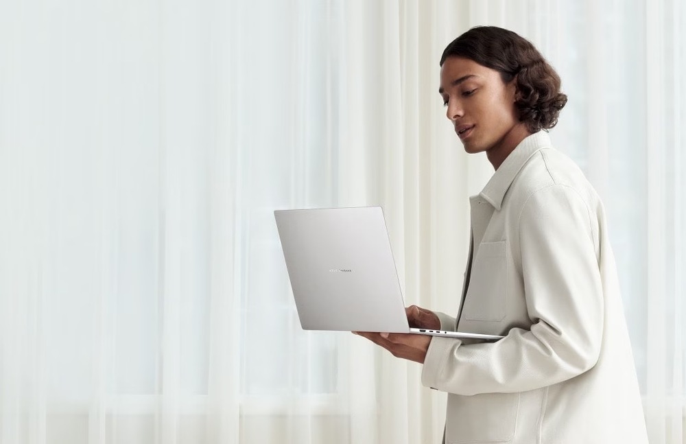 Notebook Asus Zenbook S16 OLED bílý Žena drží v jedné ruce lehký a elegantní Zenbook S16
