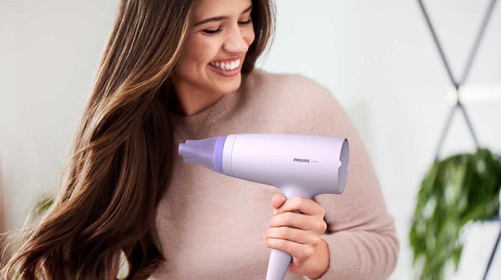 Fén Philips Series 3000 BHD341/10 růžový Smějící se žena s fénem Philips BHD341/10 Series 3000 v ruce