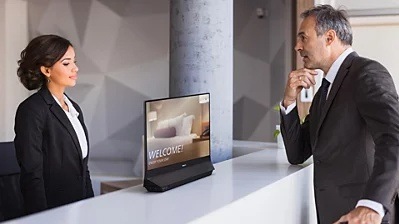 Recepční komunikuje se zákazníkem, mezi sebou mají oboustranný monitor Philips 24B2D5300/00