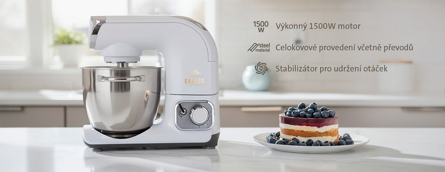 Kuchyňský robot ETA Gratus Evo Max II na kuchyňské lince vedle dortu s borůvkami, v pravo je výčet vlastností: 1 500W motor, celokovové provedení, stabilizátor a mixér součástí balení