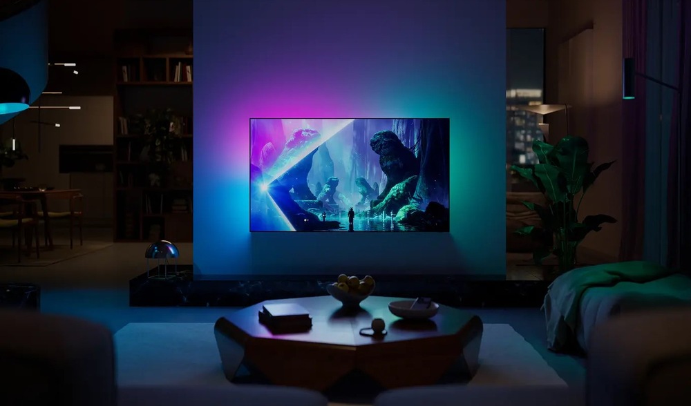 Televize Philips 55OLED801 Obrázek zachycuje technologii Ambilight, kdy LED osvětlení reaguje na dění na obrazovce barevným promítáním na zeď za televizorem.