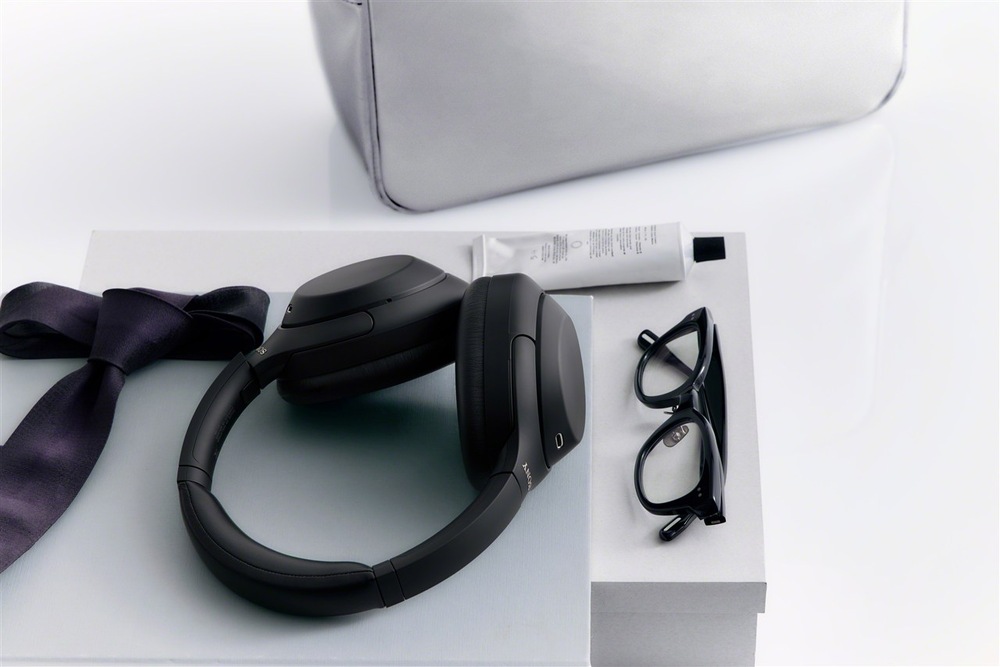 Sluchátka Sony WH-1000XM4C položená na nábytku vedle obuvi