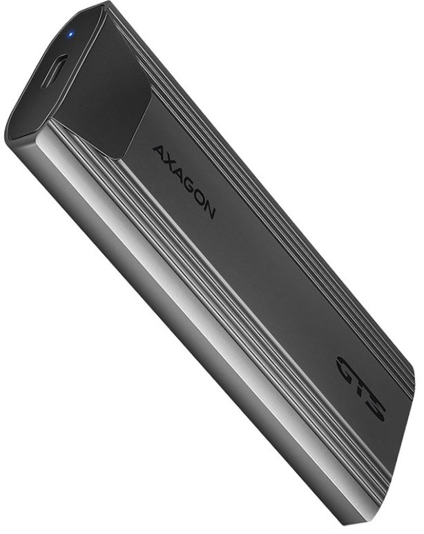 Na obrázku je šedý externí box AXAGON THIN pro M.2 SSD zachycený šikmo zepředu. Má úzký, podlouhlý tvar se zaoblenými hranami a elegantní kovové tělo s jemným podélným žebrováním po stranách. Na čele je USB-C konektor a malá modrá kontrolka, na horní straně nápis AXAGON a označení GTS. Zařízení působí kompaktně, moderně a technicky.