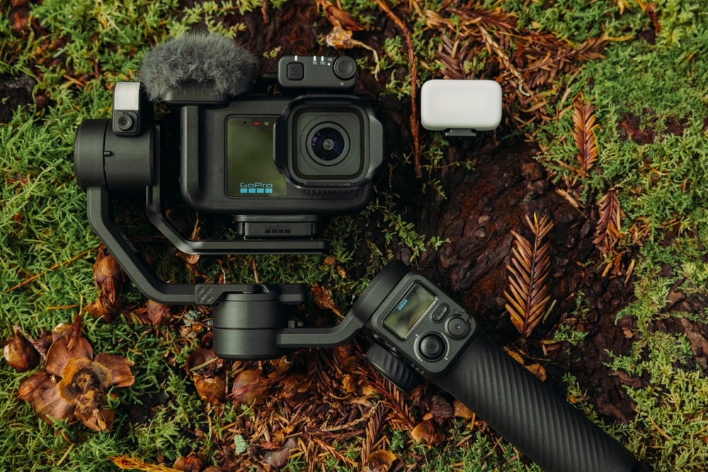 Outdoorová kamera GoPro MISSION 1 PRO Ultimate Creator Edition černá GoPro MISSION 1 PRO se stabilizátorem, mikrofonem a světlem položená na mechem porostlém kmeni