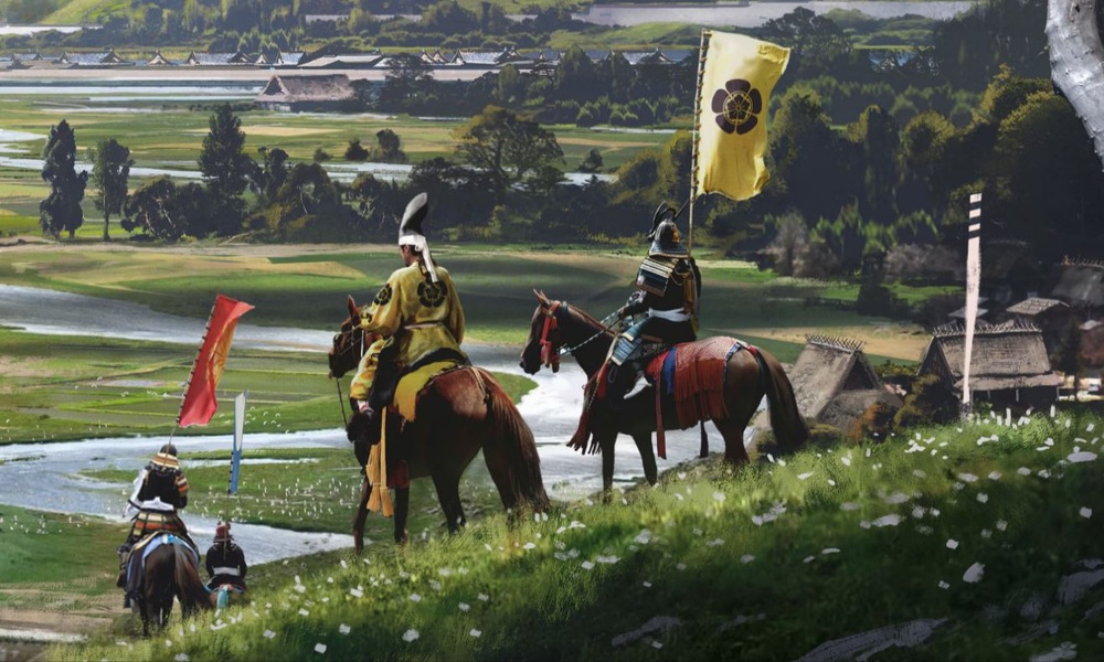 Obrázek ze hry Assassin's Creed Shadows. Záběr na postavy na koních, sjíždějící z kopce do údolí s japonskou vesnicí v pozadí..
