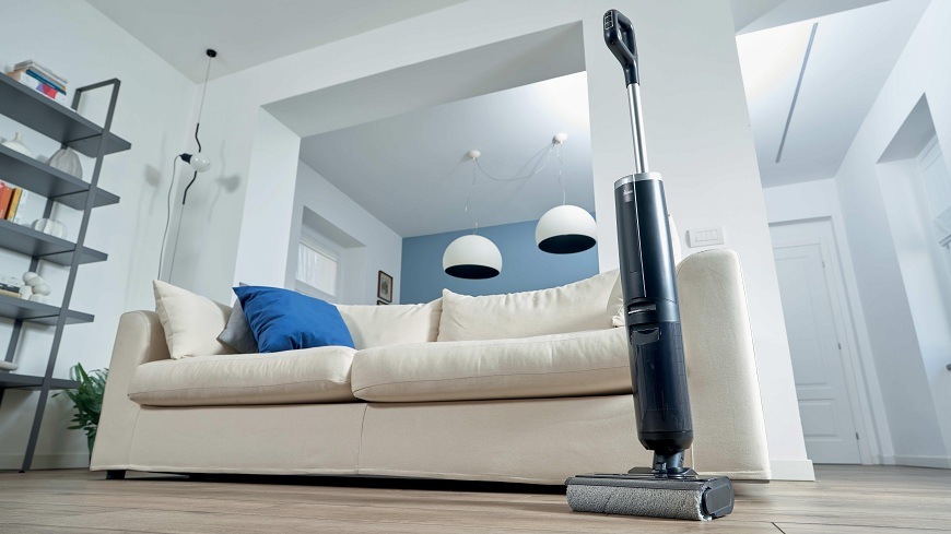 vysavač Hoover HW300 011 stojí vedle gauče uprostřed místnosti