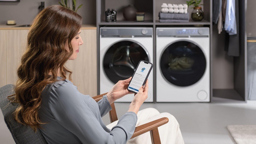 Sušička prádla Haier HD90-AQ387U1-S bílá žena se chystá k dálkovému ovládání sušičky Haier HD90-AQ387U1-S a pračky haier pomocí mobilu a aplikace hon
