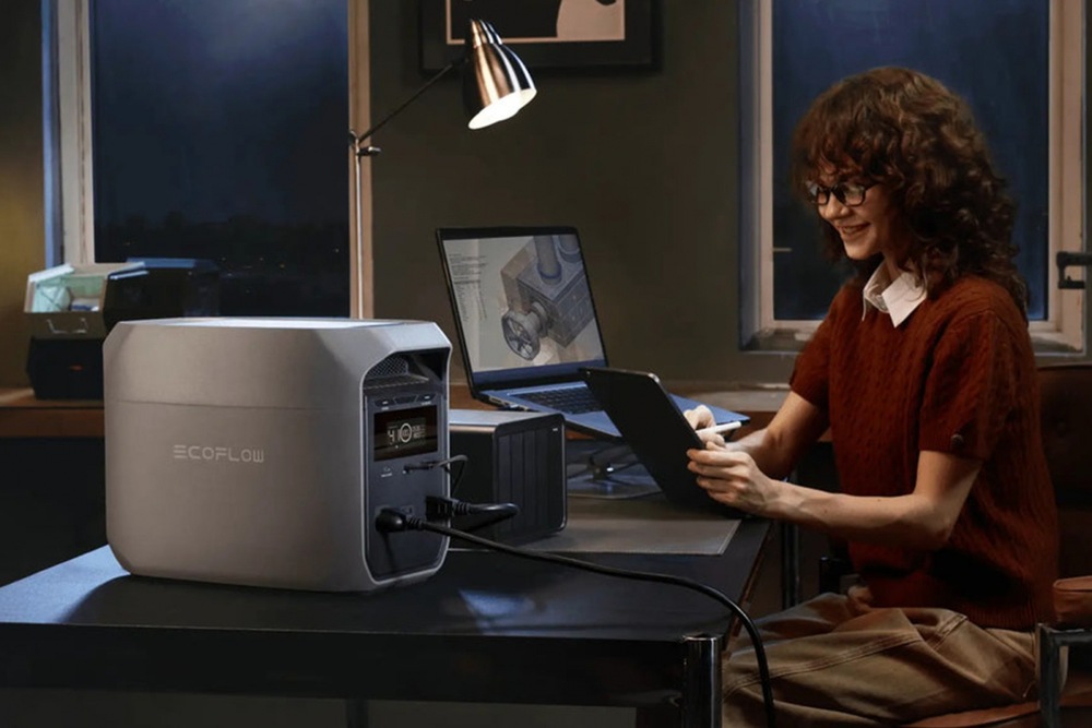 Nabíjecí stanice EcoFlow DELTA 3 Classic (1024 Wh) šedá Žena pracující v noci u stolu s notebookem napájeným ze stanice EcoFlow DELTA 2.