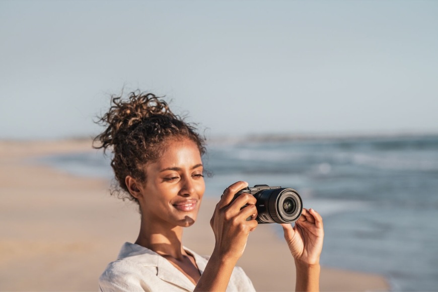 Žena natáčí video na pláži s kompaktním fotoaparátem Sony Alpha 6700 se 4K rozlišením videa