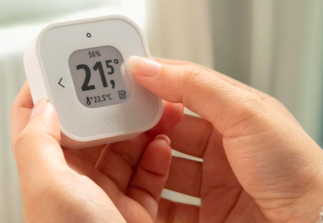 Detail ovladače Thermo Control od Eve s nastavenou teplotou 21,5 °C v ruce uživatele