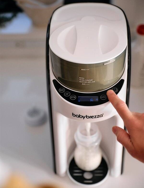 Baby Brezza Formula Pro Advanced White zachycený při přípravě dětské kojenecké lahvičky.