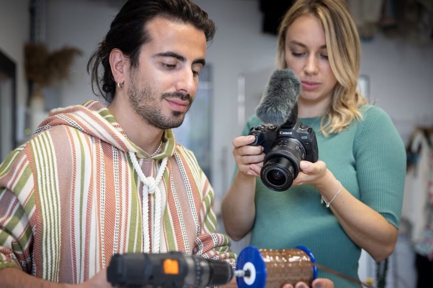 Žena natáčející video pracujícího muže s bezzrcadlovkou Canon EOS R8